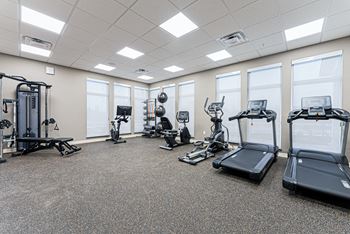 A spacious gym with a variety of equipment including treadmills, elliptical machines, and weight machines.